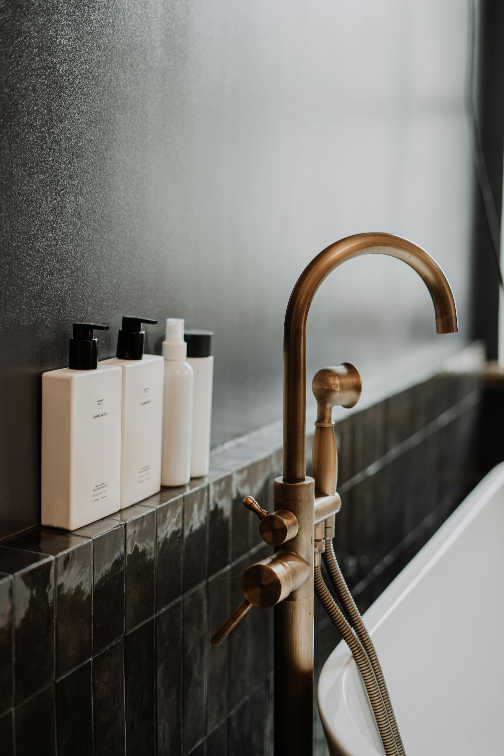 Sleek modern bathroom featuring a golden water tap and minimalist bottles.